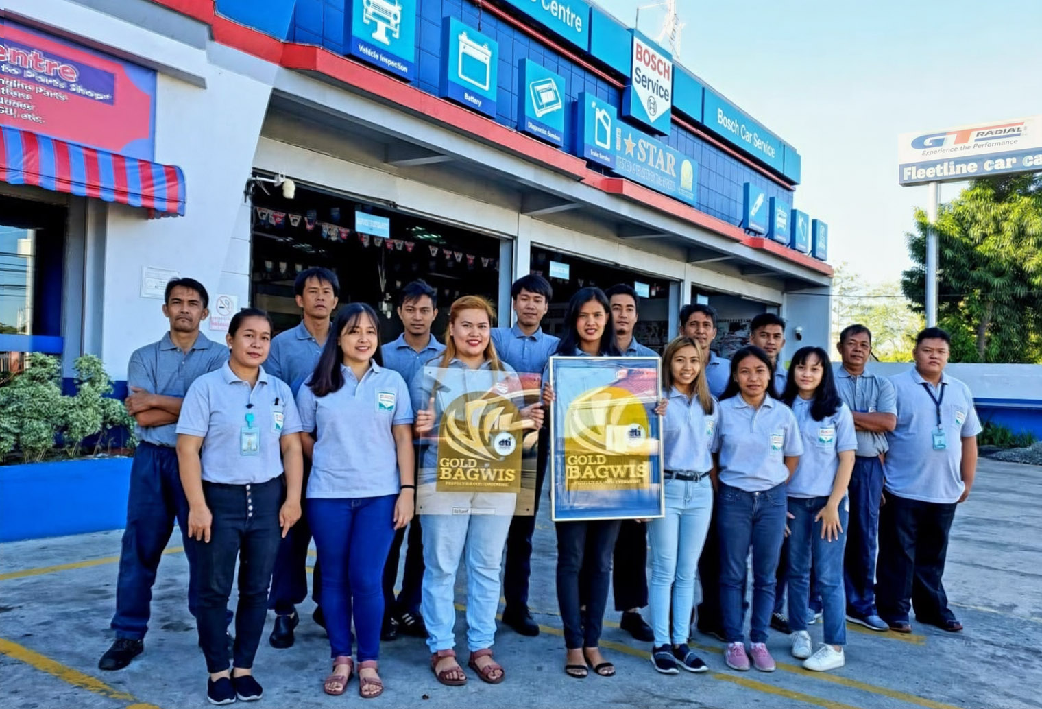 Northeast Car Care Centre team holding two DTI Gold Bagwis awards in front of the service centre